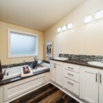 Skyline Homes Westridge 1492CT Manufactured Home Master bathroom featuring double vanity, oval bathtub, shower, linen cabinet, small window, toilet