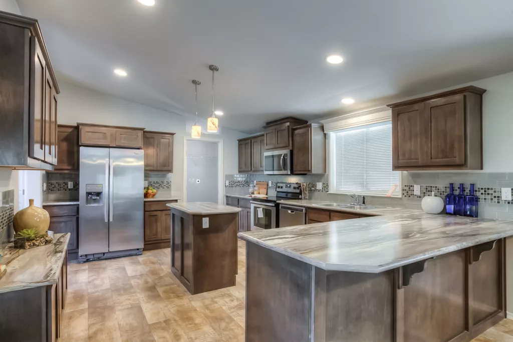 Manufactured kitchen with tile above counters, granite counter tops, island, and plank-look floors