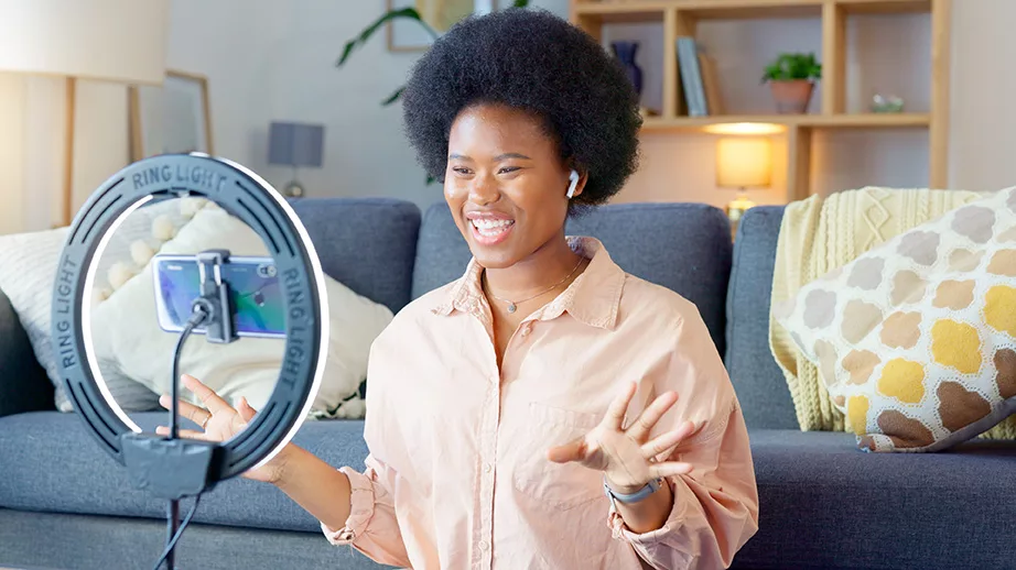 Young, smiling African American woman vlogging in her stylish living room. 