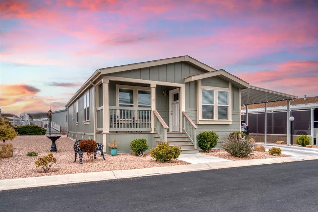 A beautiful craftsman style manufactured home in oregon with a blue, pink, orange, and purple sunset in the background