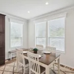 dining nook with 3 windows overlooking the front lawn attached to an open-concept kitchen