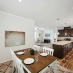 dining nook attached to an open kitchen concept with kitchen island and bar-top, granite counters, dark wood cabinets, nickel hardware, and stainless steel appliances