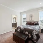 spacious primary bedroom with chocolate brown carpeting, private primary bath, recessed lighting, and windows on either side of the bed