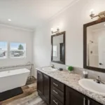 primary bath with double sink vanity and dual mirrors with tile backsplash, dark wood cabinets, and nickel hardware, with a modern bathtub