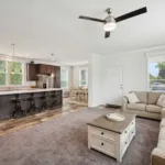 spacious living room across for an open-concept kitchen with kitchen island, bar seating, and granite counters