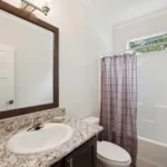 second bathroom with single sink, granite countertop, nickel hardware, and dark wood cabinets