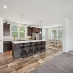 open kitchen concept with kitchen island and bar seating, granite counters, dark wood cabinets, nickel hardware, and stainless steel appliances