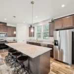 open kitchen concept with kitchen island and bar seating, granite counters, dark wood cabinets, nickel hardware, and stainless steel appliances