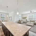 granite kitchen island with bar seating and pendant lighting across from a living room, dining nook, and front door