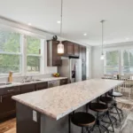 dining nook attached to an open kitchen concept with kitchen island and bar-top, granite counters, dark wood cabinets, nickel hardware, and stainless steel appliances