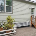 backdoor entrance with lattice skirting around the bottom of the home foundation