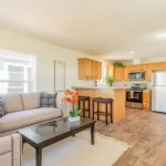 open living room leading into an open kitchen with lots of windows for natural lighting