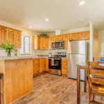 open kitchen with double sinks, stainless steel appliances, rich wood cabinets, granite counters, bar seating, and nickel hardware