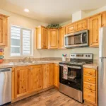 open kitchen with double sinks, stainless steel appliances, rich wood cabinets, granite counters, and nickel hardware