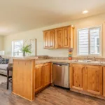 open kitchen with double sinks, stainless steel appliances, rich wood cabinets, granite counters, and nickel hardware