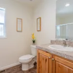 single sink in granite counter with rich wood cabinets and porcelain toilet