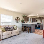 open living room leading into an open kitchen with bar seating, dark wood cabinets, and stainless steel appliances