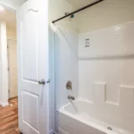 private bathroom with traditional tub shower opening out into the walk-in closet attached to the primary bedroom