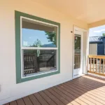 glass front door and large window looking out over the covered wooden deck