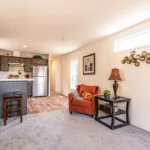 open living room leading into an open kitchen with bar seating, dark wood cabinets, and stainless steel appliances