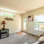 open living room with front door leading out to a small, covered deck