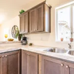 double sink kitchen with granite counters, nickel hardware, and dark wood cabinets