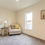 plush white chair with yellow and patterned throw pillows next to a round end table