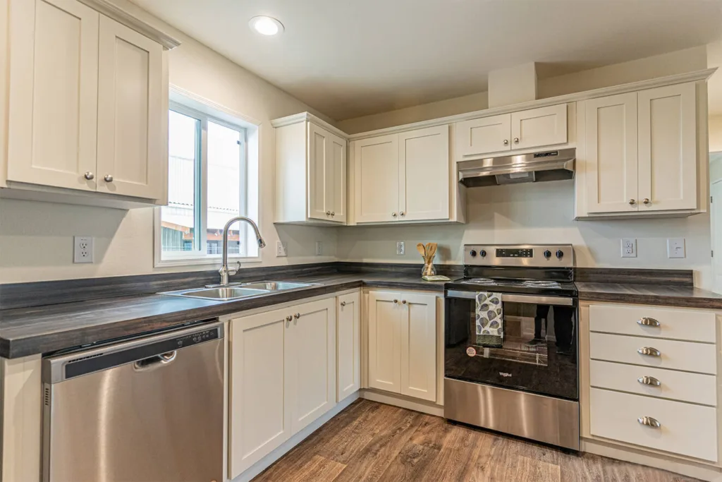 open kitchen with dark granite counters, stainless steel appliances, white cabinets, and nickel hardware
