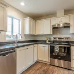 open kitchen with dark granite counters, stainless steel appliances, white cabinets, and nickel hardware