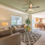 living room with grey modern sofa and loveseat, glass-top coffee table, and try ceiling in a sage green accent color