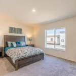 primary bedroom with dark grey wood furniture, queen size bed, and 2 nightstands with a window overlooking the backyard